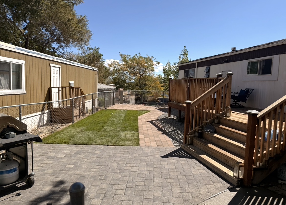 Backyard paver patio with turf strip and wood deck